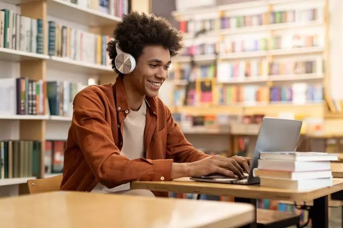 Aluno estudando no computador com fone